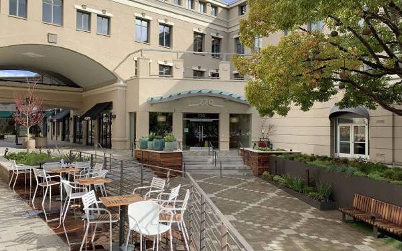 A patio with tables and chairs outside of a building.