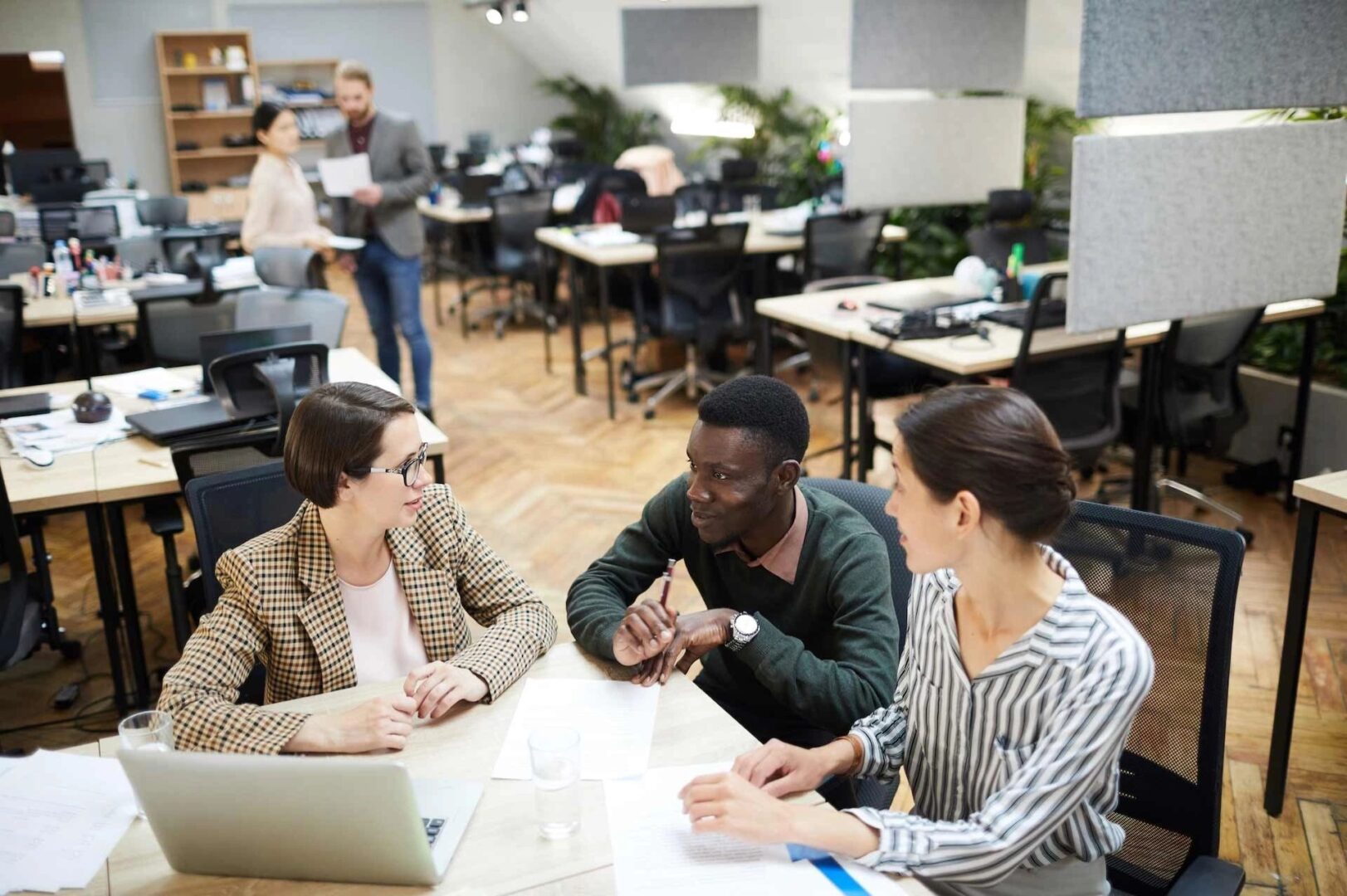 Three people sitting at a table in an office.